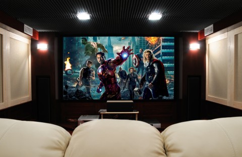 white plush seating in front of a large home theater screen showing superheroes