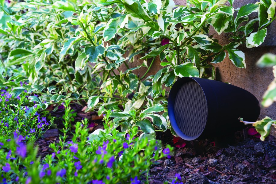A Sonance outdoor speaker installed in a garden. 